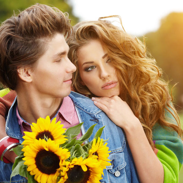 young woman hugging young man in field with sunflowers, first sexual experience story